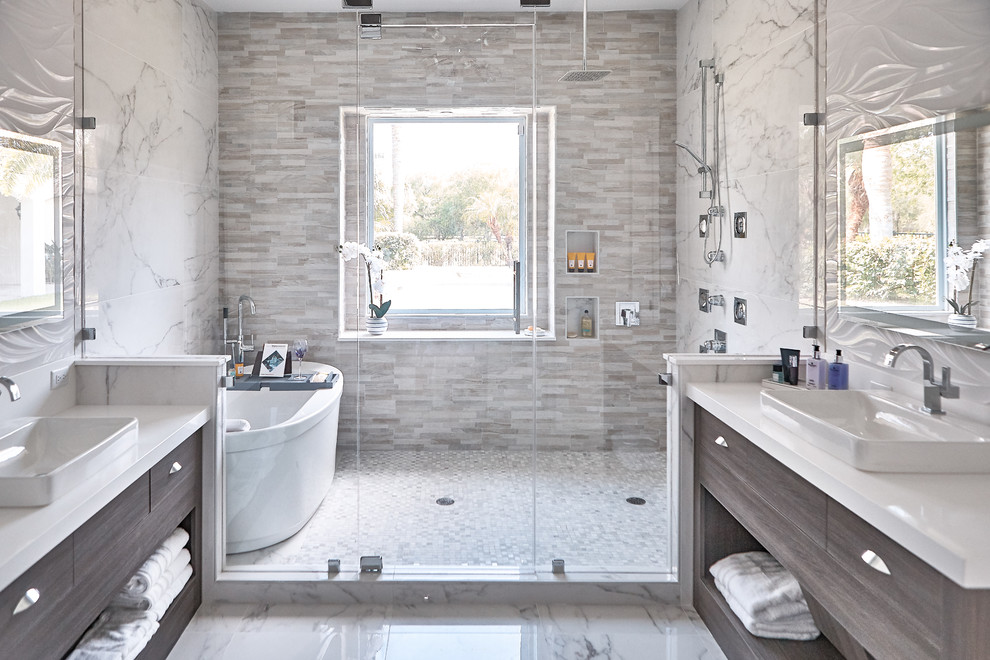 Design ideas for a large contemporary master wet room bathroom in Austin with flat-panel cabinets, dark wood cabinets, a freestanding tub, white tile, marble, white walls, marble floors, a vessel sink, solid surface benchtops, white floor, a hinged shower door and white benchtops.