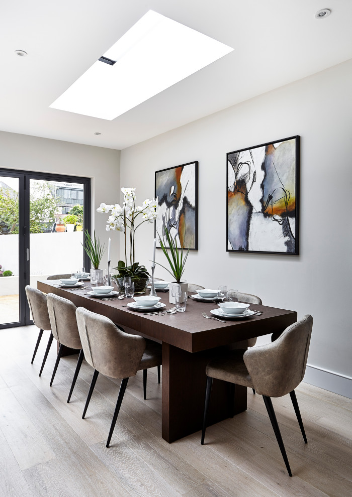 Photo of a contemporary dining room in London with white walls, light hardwood floors and beige floor.