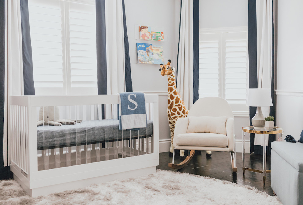 This is an example of a mid-sized modern nursery for boys in Los Angeles with white walls, dark hardwood floors and white floor.