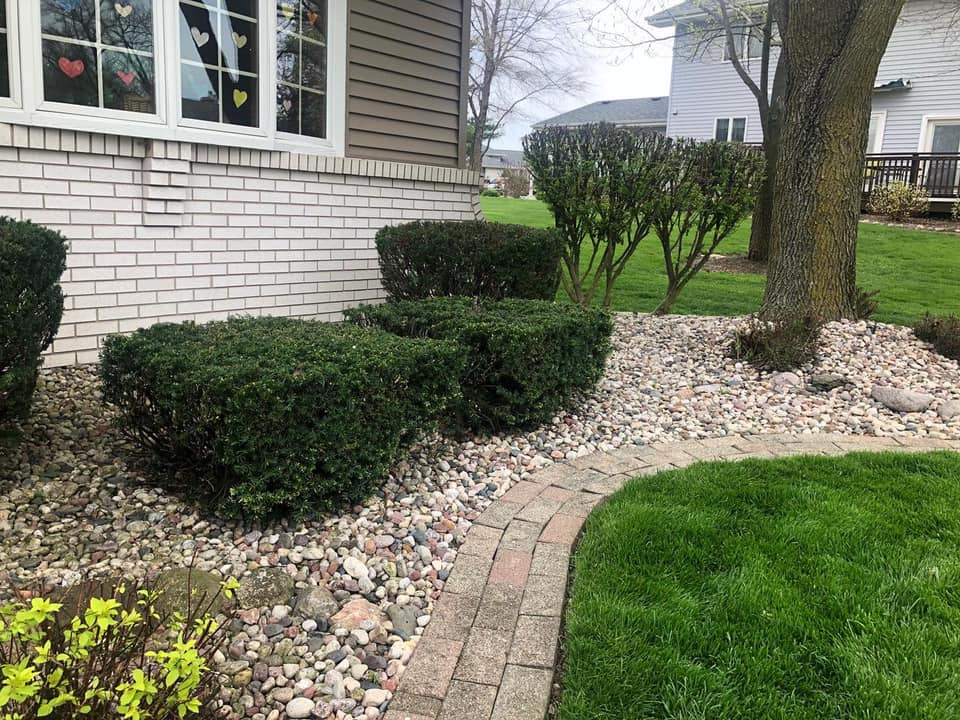 This is an example of a mid-sized front yard partial sun formal garden for spring in Chicago with with flowerbed and river rock.