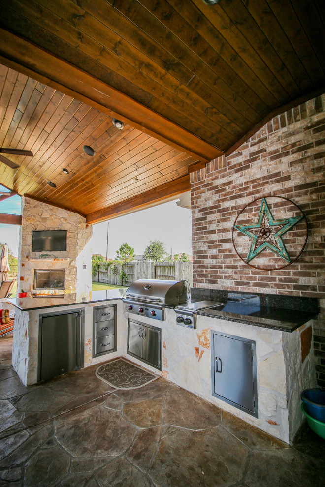Large traditional backyard patio in Houston with an outdoor kitchen, stamped concrete and a roof extension.