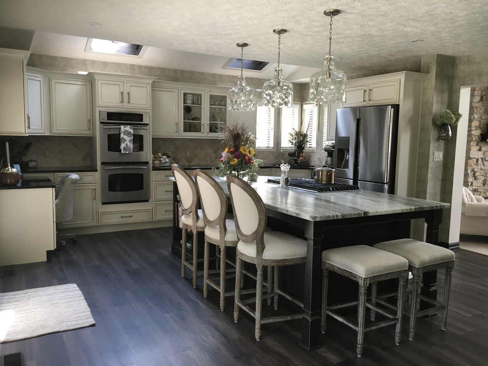 Eat-in kitchen - large transitional u-shaped laminate floor and gray floor eat-in kitchen idea with an undermount sink, recessed-panel cabinets, white cabinets, granite countertops, white backsplash, ceramic backsplash, stainless steel appliances, an island and black countertops