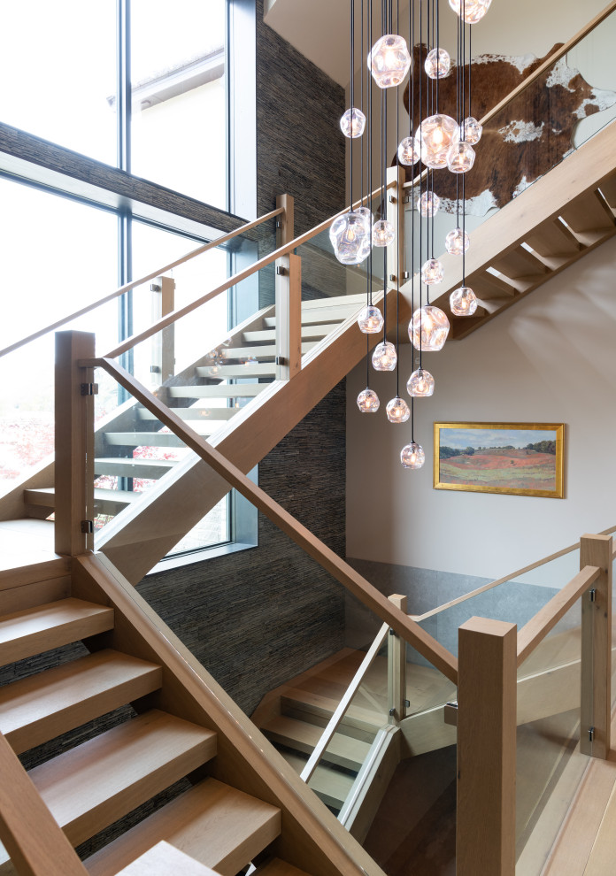 This is an example of a large country wood floating staircase in Dallas with open risers and glass railing.