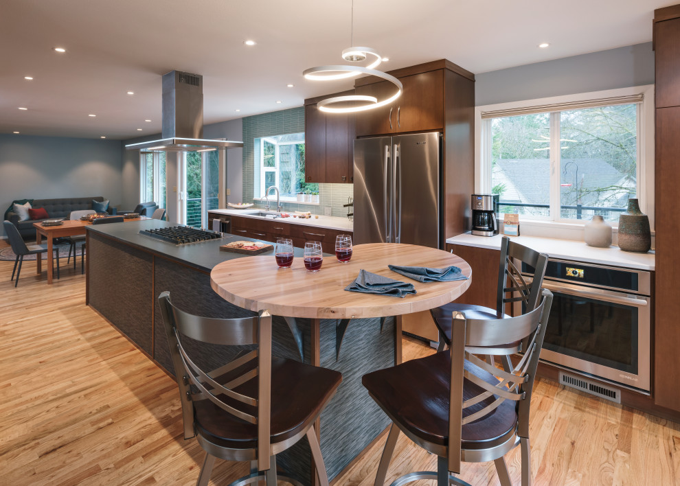 Photo of a mid-sized contemporary galley eat-in kitchen in Portland with an undermount sink, flat-panel cabinets, dark wood cabinets, quartz benchtops, blue splashback, glass tile splashback, stainless steel appliances, medium hardwood floors, with island, brown floor and multi-coloured benchtop.