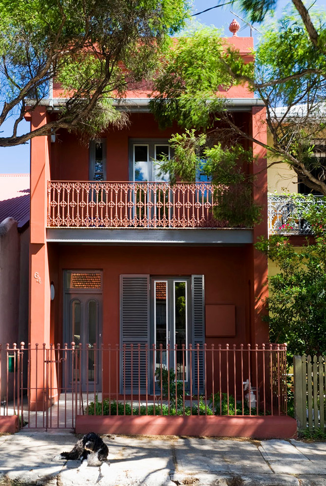Design ideas for a mid-sized traditional two-storey stucco red exterior in Sydney with a hip roof.