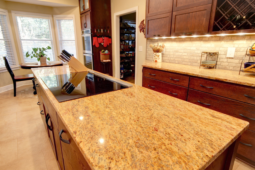 Transitional eat-in kitchen photo in Miami with an undermount sink, shaker cabinets, brown cabinets, granite countertops, beige backsplash, stone tile backsplash and stainless steel appliances