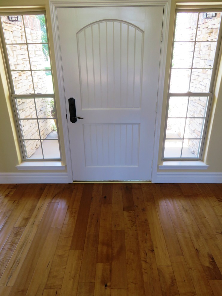 This is an example of a mid-sized country front door in Other with yellow walls, light hardwood floors, a single front door and a white front door.
