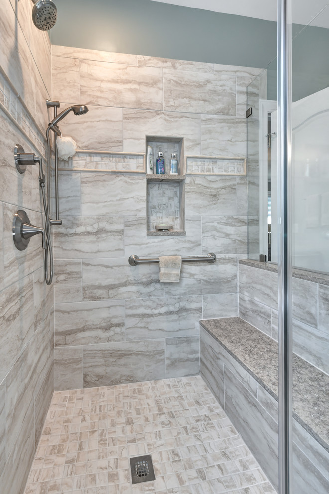 Beach style master bathroom in Charleston with raised-panel cabinets, dark wood cabinets, a two-piece toilet, beige tile, porcelain tile, blue walls, porcelain floors, an undermount sink, granite benchtops, beige floor, a hinged shower door and beige benchtops.