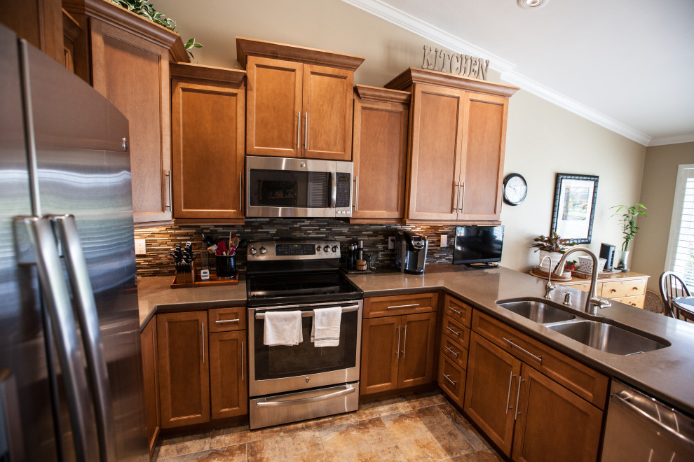 Mid-sized u-shaped ceramic tile and vaulted ceiling kitchen photo with an undermount sink, shaker cabinets, brown cabinets, wood countertops, mosaic tile backsplash, stainless steel appliances and brown countertops