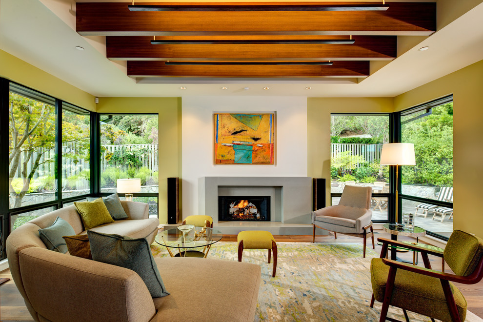 This is an example of a mid-sized midcentury formal open concept living room in San Francisco with white walls, medium hardwood floors, a standard fireplace, a concrete fireplace surround and no tv.