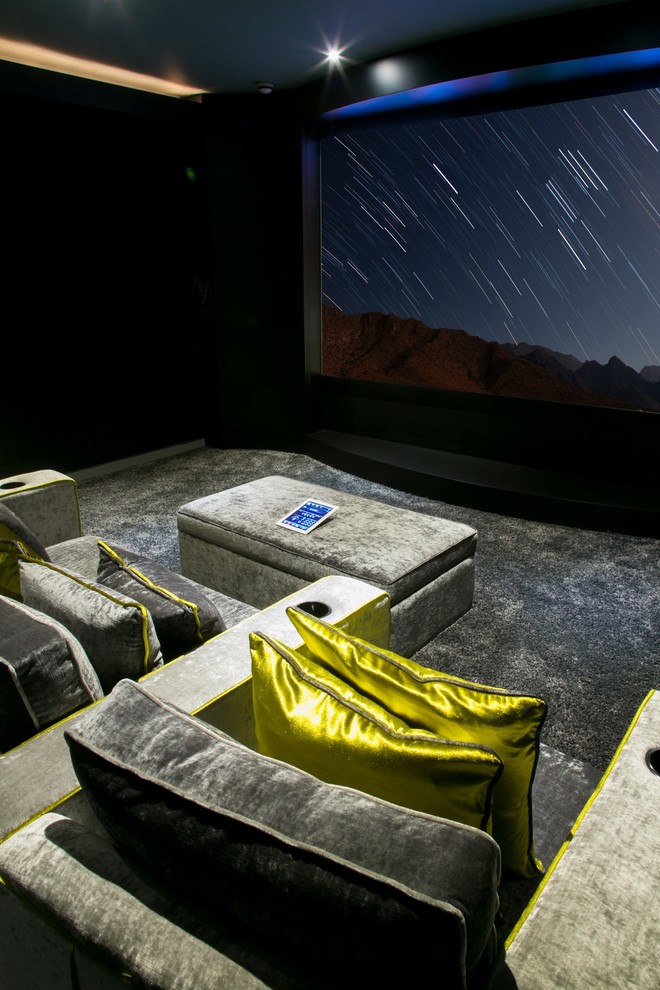 This is an example of a mid-sized eclectic enclosed home theatre in London with black walls, carpet and a projector screen.