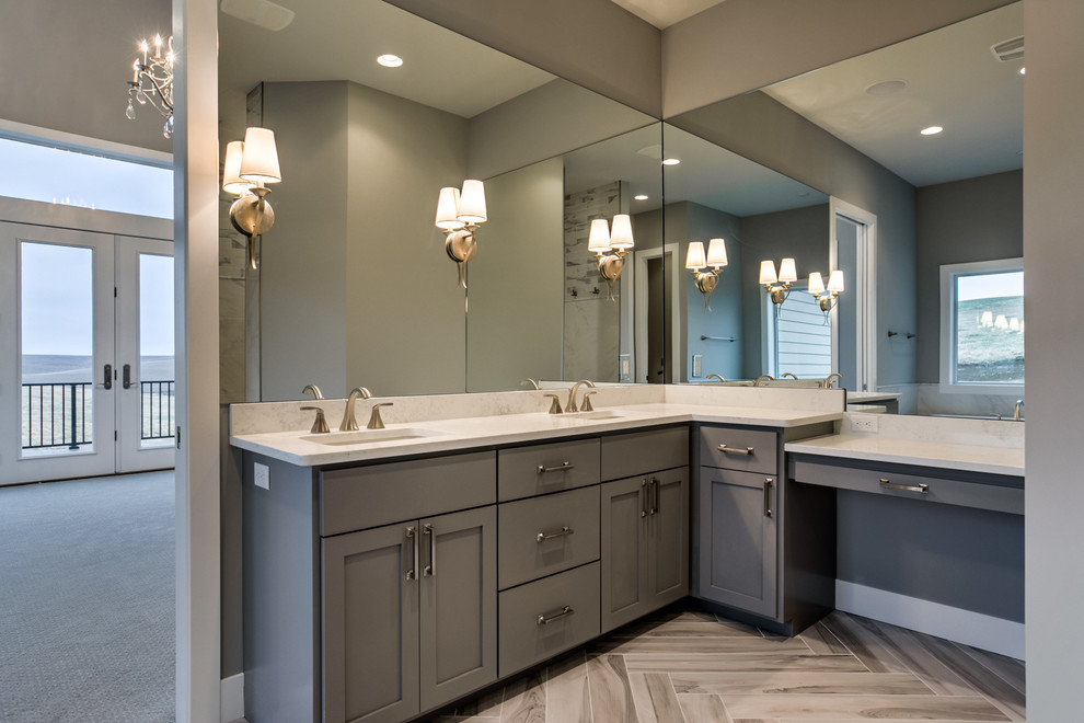 Photo of a large country powder room in Omaha with shaker cabinets, grey cabinets, grey walls, a drop-in sink, solid surface benchtops, brown floor and porcelain floors.