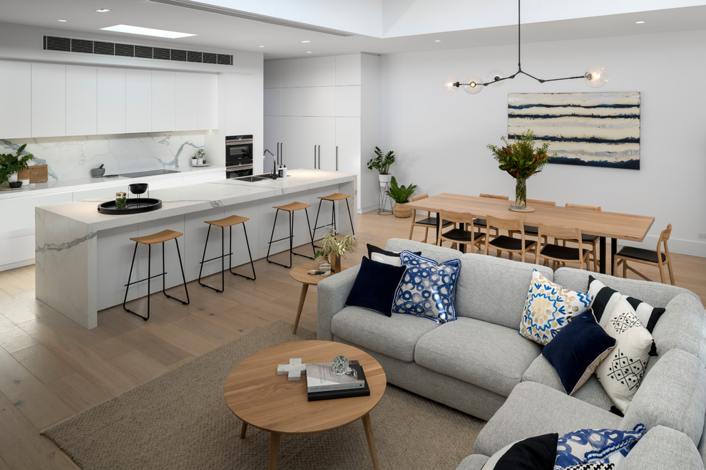 Inspiration for a mid-sized beach style open plan dining in Adelaide with white walls, light hardwood floors, a standard fireplace, a plaster fireplace surround and brown floor.