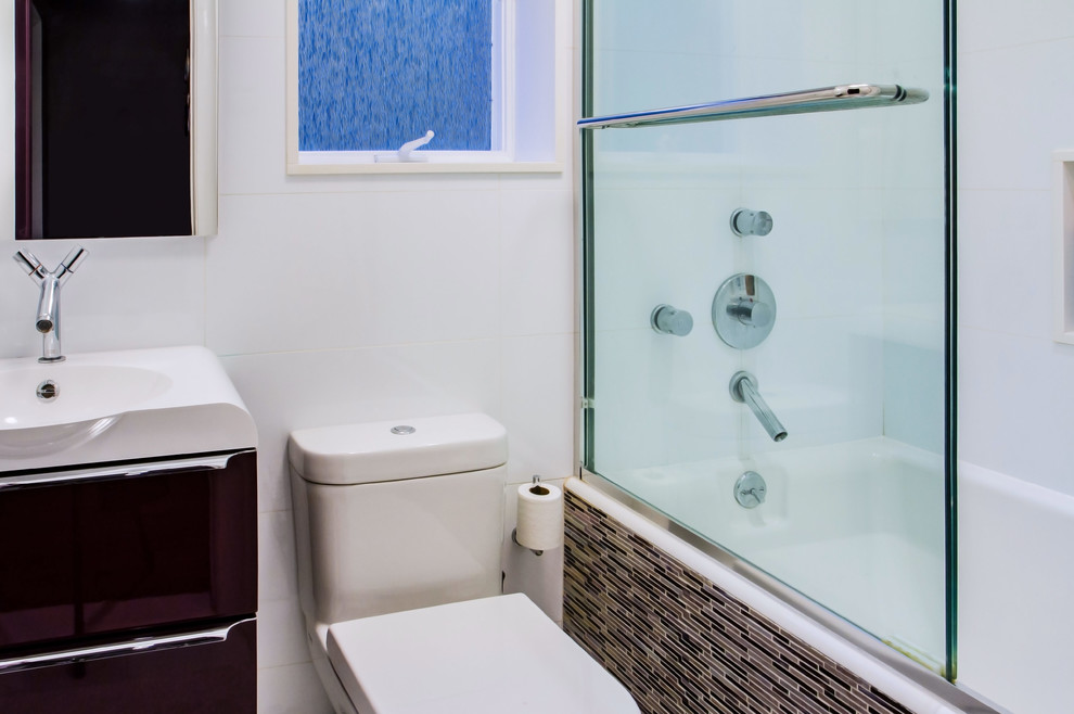 Mid-sized contemporary bathroom in New York with flat-panel cabinets, purple cabinets, a drop-in tub, a shower/bathtub combo, a one-piece toilet, an integrated sink, solid surface benchtops and a sliding shower screen.