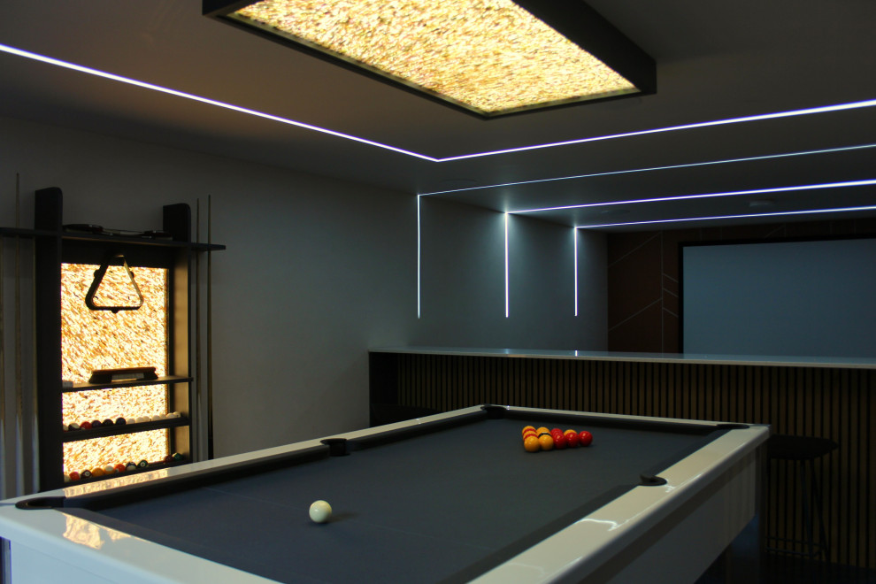 This is an example of a large modern open plan games room in Manchester with a game room, a wall mounted tv, blue floors, panelled walls and feature lighting.