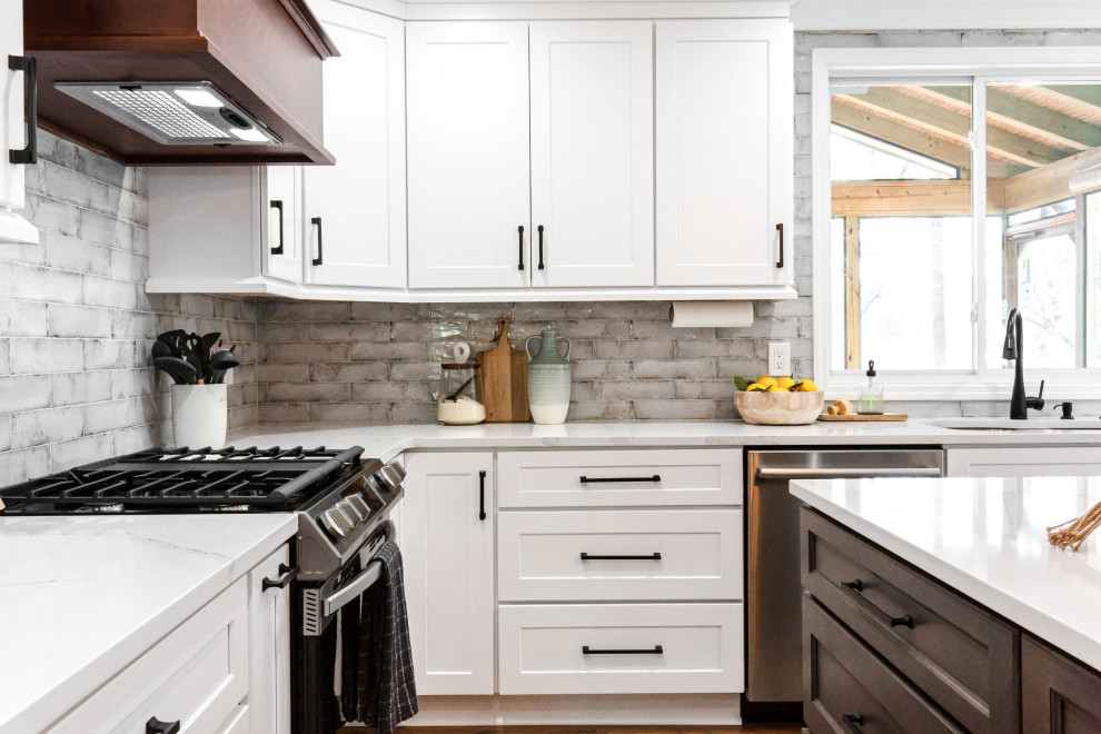 This is an example of a medium sized rural u-shaped enclosed kitchen in Atlanta with a submerged sink, shaker cabinets, white cabinets, engineered stone countertops, grey splashback, metro tiled splashback, stainless steel appliances, medium hardwood flooring, an island, brown floors and white worktops.