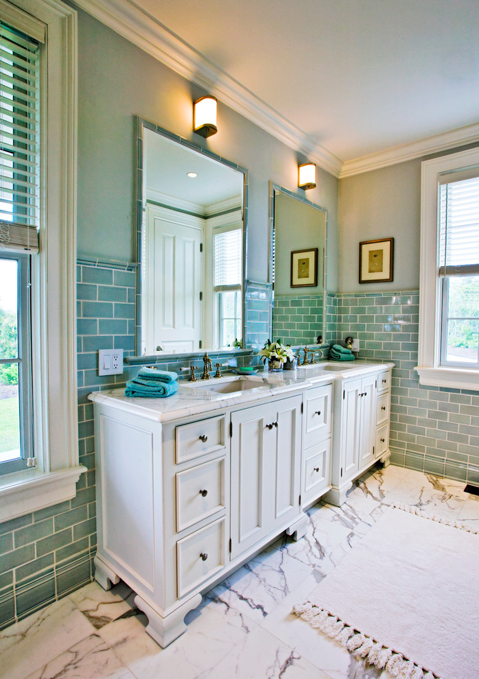 This is an example of a traditional bathroom with an undermount sink, recessed-panel cabinets, white cabinets, blue tile, subway tile and blue walls.