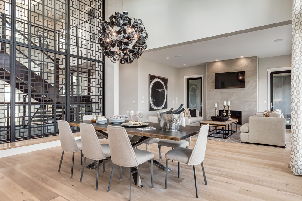 Mid-sized contemporary open plan dining in Calgary with light hardwood floors, white walls, a standard fireplace, a tile fireplace surround and beige floor.