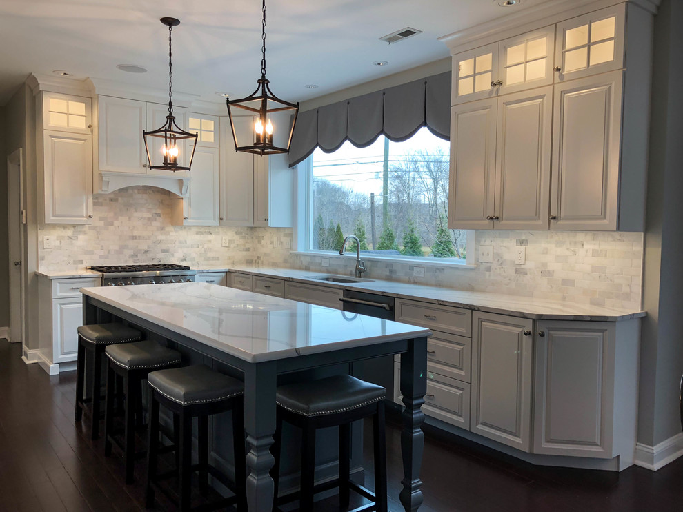 This is an example of a large transitional u-shaped eat-in kitchen in Philadelphia with an integrated sink, shaker cabinets, white cabinets, marble benchtops, multi-coloured splashback, ceramic splashback, stainless steel appliances, dark hardwood floors, with island, black floor and multi-coloured benchtop.