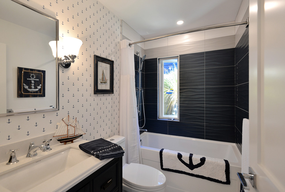 Inspiration for a mid-sized beach style 3/4 bathroom in Vancouver with black cabinets, a shower/bathtub combo, a one-piece toilet, black and white tile, white walls, a drop-in sink, a shower curtain, white benchtops, a single vanity, a built-in vanity and wallpaper.
