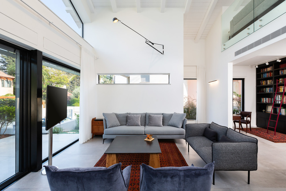 1960s open concept concrete floor and gray floor living room library photo in Tel Aviv with white walls, no fireplace and a tv stand