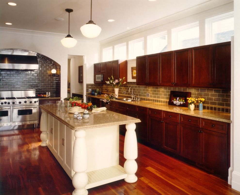 This is an example of a transitional eat-in kitchen in Detroit with recessed-panel cabinets, medium wood cabinets, black splashback and stainless steel appliances.