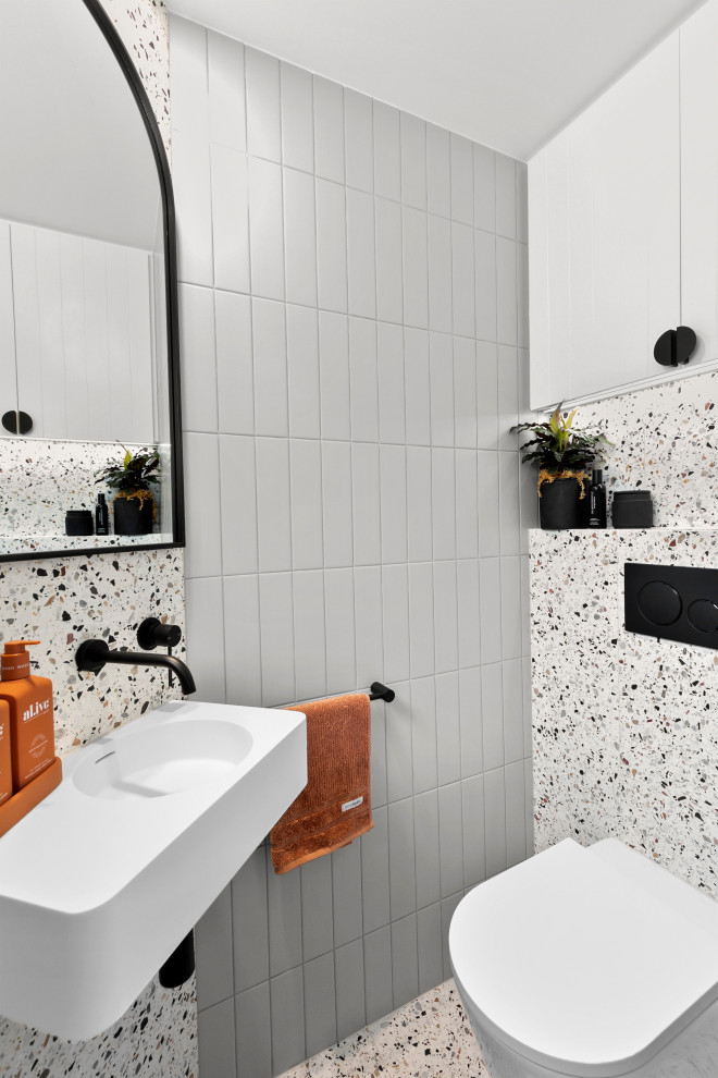 Kleine Moderne Gästetoilette mit weißen Schränken, Toilette mit Aufsatzspülkasten, grauen Fliesen, Metrofliesen, bunten Wänden, Terrazzo-Boden, Wandwaschbecken, Mineralwerkstoff-Waschtisch, buntem Boden, weißer Waschtischplatte und schwebendem Waschtisch in Sydney