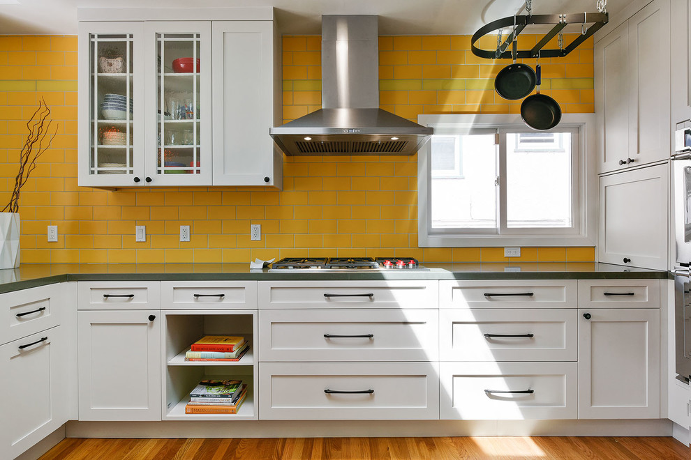 Inspiration for a mid-sized transitional u-shaped kitchen pantry in San Francisco with an undermount sink, shaker cabinets, white cabinets, quartz benchtops, yellow splashback, ceramic splashback, stainless steel appliances, medium hardwood floors, a peninsula, brown floor and grey benchtop.