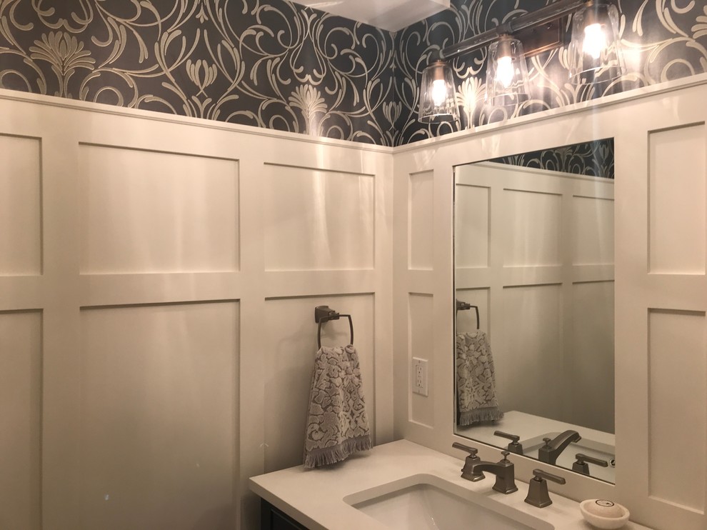 Photo of a mid-sized traditional powder room in Toronto with furniture-like cabinets, black cabinets, a two-piece toilet, white walls, ceramic floors, an undermount sink, engineered quartz benchtops, grey floor and white benchtops.