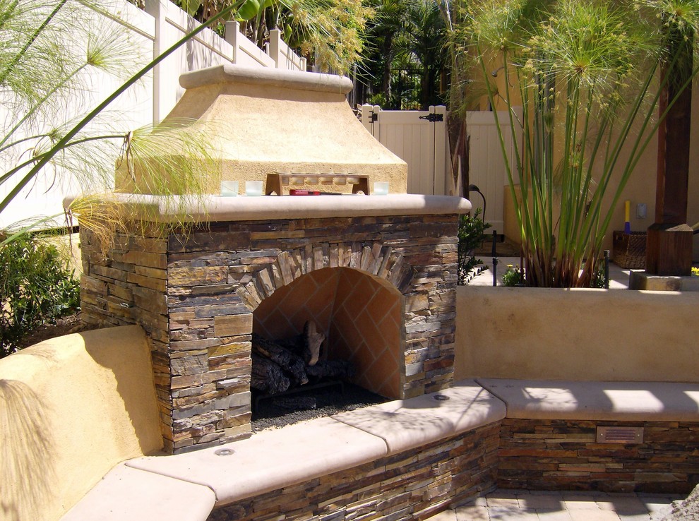 Design ideas for a small mediterranean backyard patio in San Diego with with fireplace, concrete pavers and no cover.