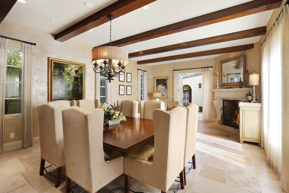 Inspiration for a mid-sized mediterranean open plan dining in Orange County with beige walls, limestone floors, a corner fireplace, a stone fireplace surround and beige floor.