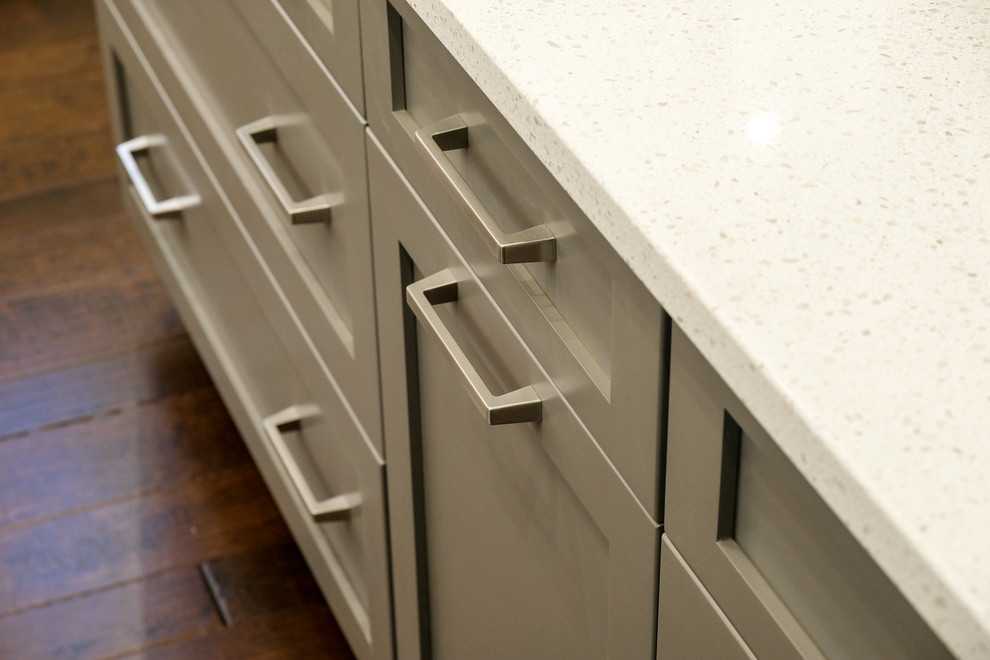 Large transitional u-shaped dark wood floor and brown floor eat-in kitchen photo with a farmhouse sink, recessed-panel cabinets, white cabinets, quartz countertops, white backsplash, stainless steel appliances, an island and white countertops