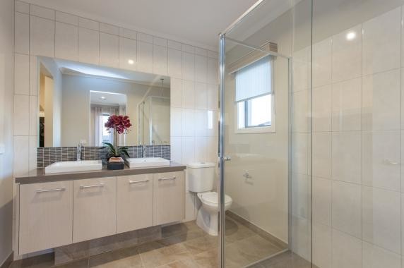 Photo of an eclectic bathroom in Melbourne with flat-panel cabinets, white cabinets, a corner shower, a two-piece toilet, white tile, white walls, limestone floors and a vessel sink.