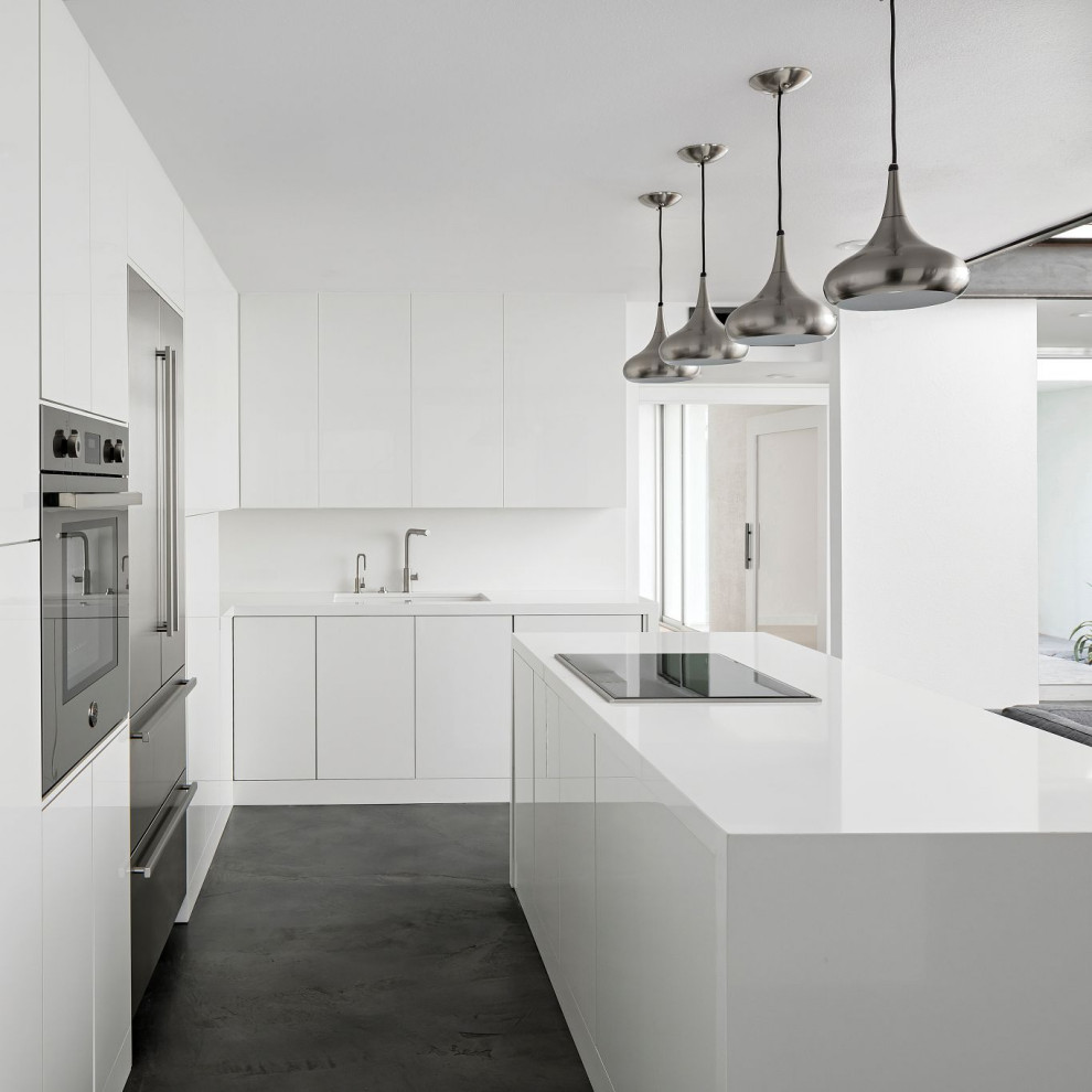 Example of a minimalist l-shaped gray floor open concept kitchen design in Phoenix with an undermount sink, flat-panel cabinets, white cabinets, quartz countertops, white backsplash, quartz backsplash, stainless steel appliances, an island and white countertops