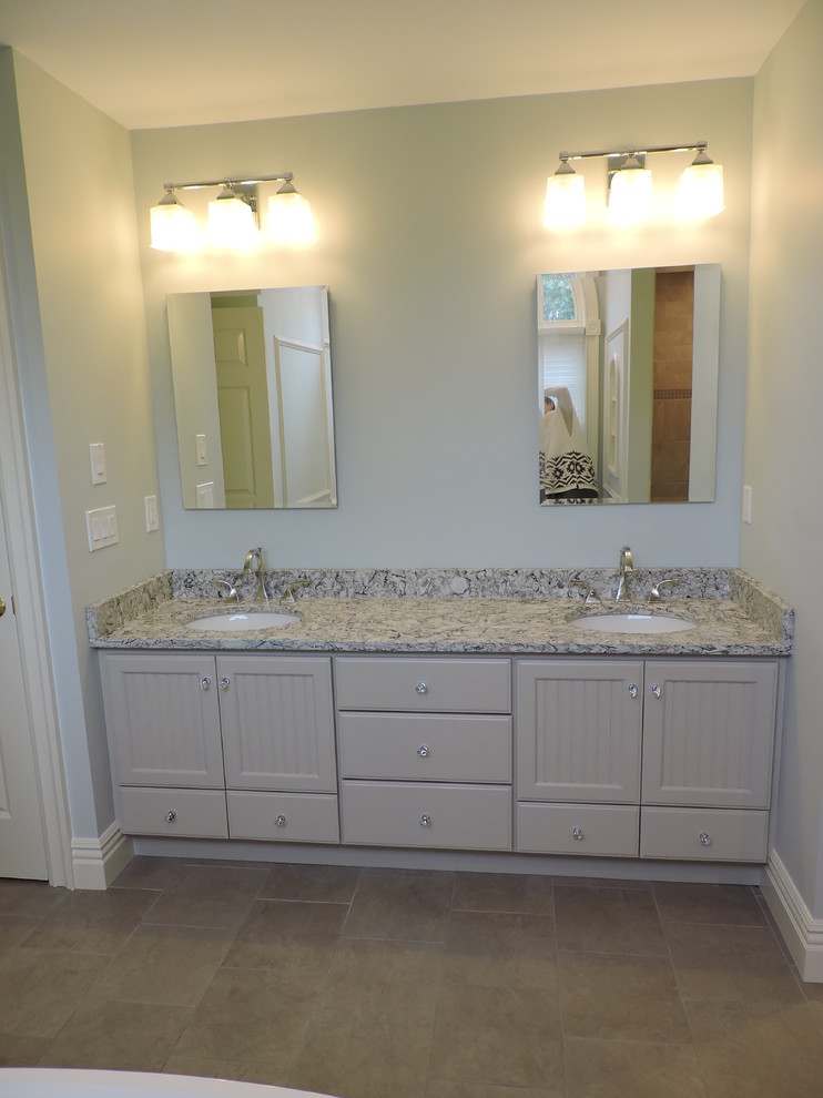Large traditional master bathroom in New York with beaded inset cabinets, beige cabinets, a freestanding tub, a corner shower, a two-piece toilet, gray tile, stone slab, grey walls, travertine floors, an undermount sink and granite benchtops.