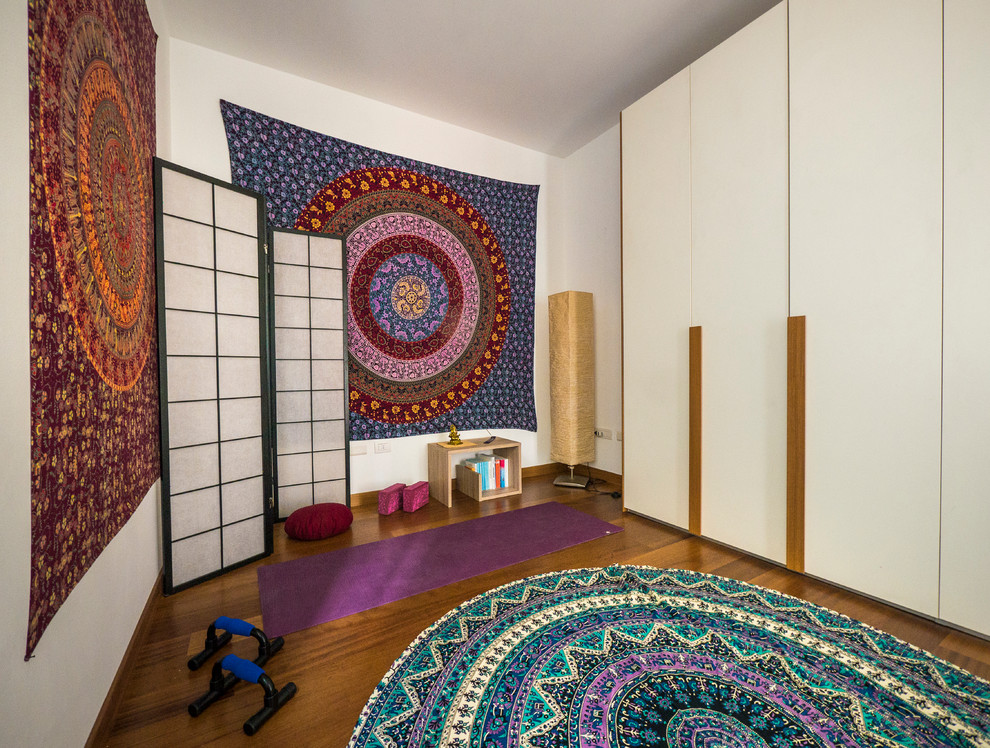 Mid-sized eclectic home yoga studio in Milan with white walls and medium hardwood floors.