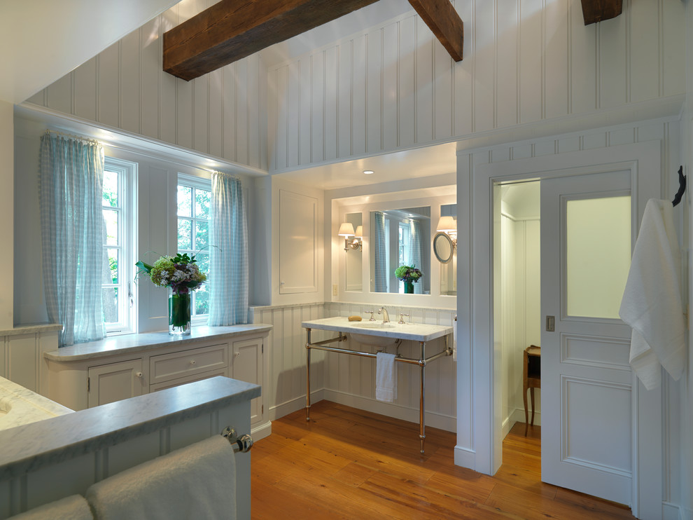 Traditional bathroom in Boston with a console sink, furniture-like cabinets, white cabinets and medium hardwood floors.