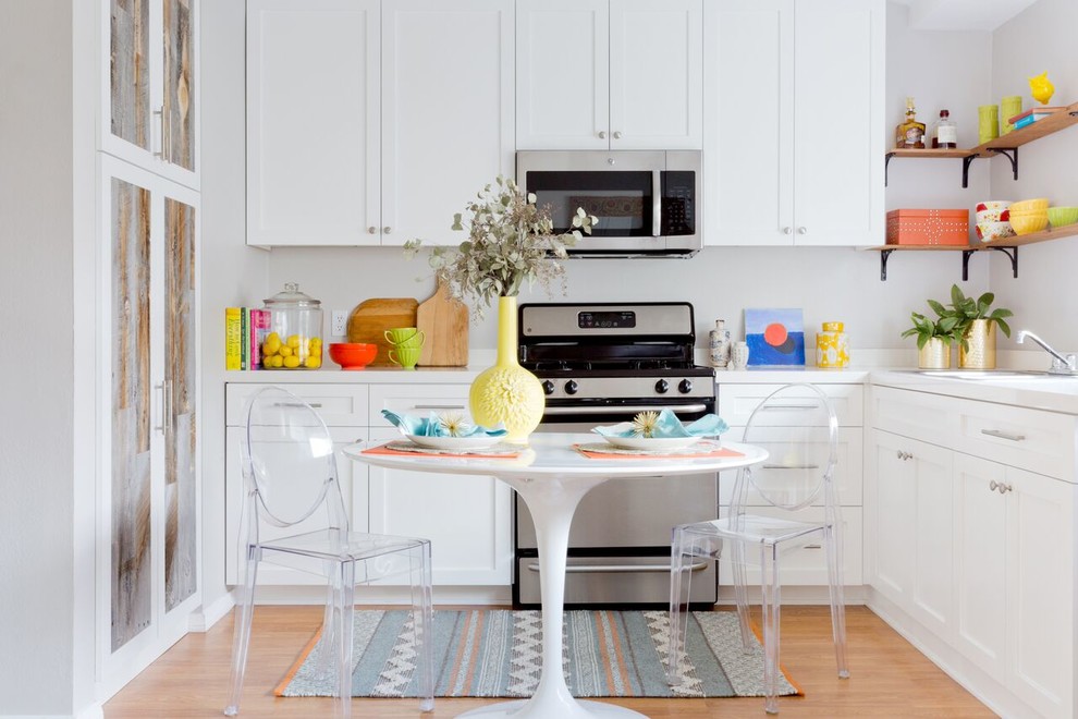 Example of a small eclectic l-shaped light wood floor and brown floor eat-in kitchen design in Los Angeles with a double-bowl sink, shaker cabinets, white cabinets, quartz countertops, white backsplash, stainless steel appliances and no island