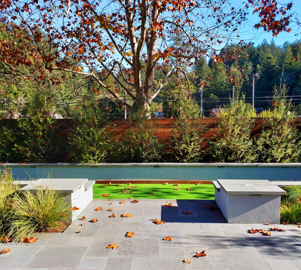 Ispirazione per un giardino minimalista esposto a mezz'ombra di medie dimensioni e in cortile in autunno con pavimentazioni in pietra naturale e recinzione in legno