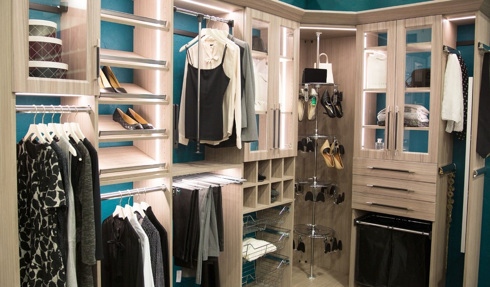 This is an example of a small contemporary gender-neutral walk-in wardrobe in Other with glass-front cabinets and light wood cabinets.