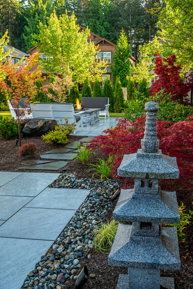 This is an example of a mid-sized asian backyard partial sun garden in Seattle with a fire feature and natural stone pavers.