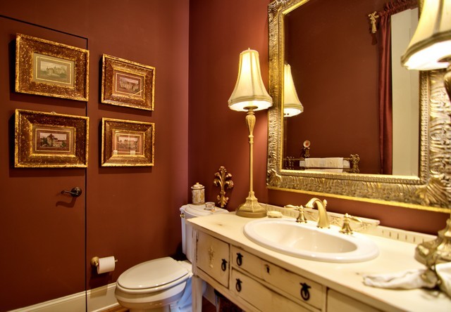 Esempio di un bagno di servizio boho chic di medie dimensioni con lavabo da incasso, consolle stile comò, ante con finitura invecchiata, top in marmo, WC monopezzo, pareti rosse e pavimento in legno massello medio