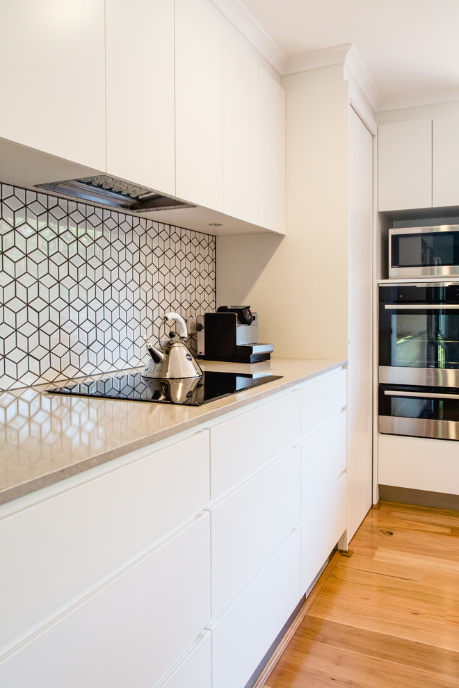 Contemporary l-shaped kitchen in Canberra - Queanbeyan with a double-bowl sink, white cabinets, mosaic tile splashback and stainless steel appliances.