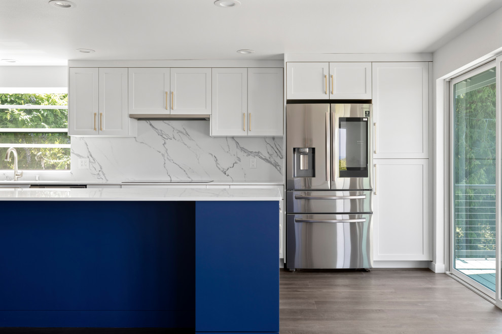 Open concept kitchen - large transitional single-wall vinyl floor, brown floor and vaulted ceiling open concept kitchen idea in Seattle with an undermount sink, shaker cabinets, white cabinets, quartz countertops, white backsplash, quartz backsplash, stainless steel appliances, an island and white countertops