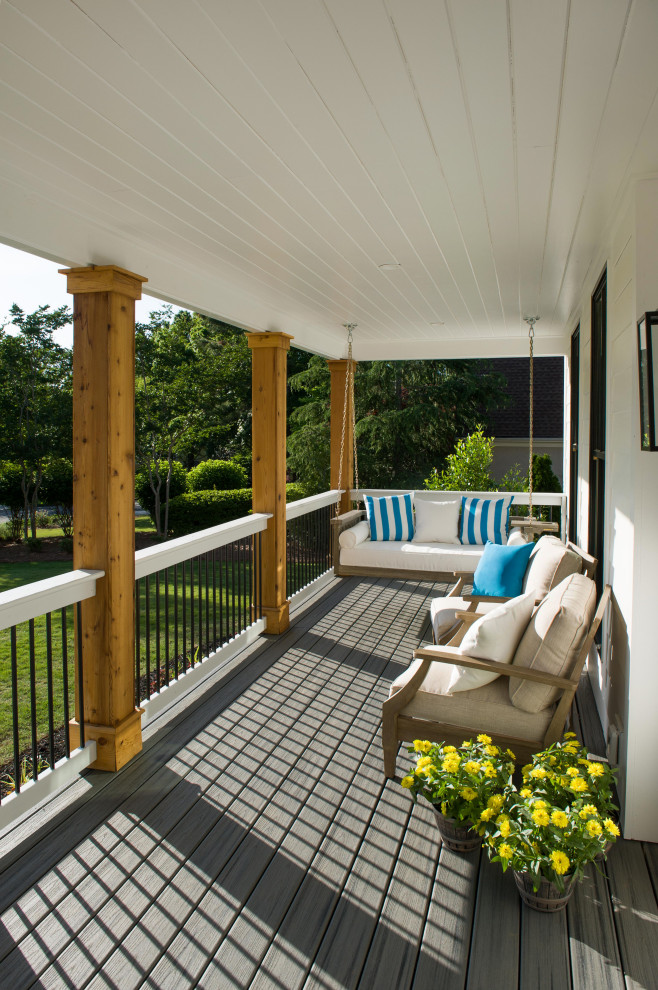 Cette image montre un grand porche d'entrée de maison avant rustique avec une terrasse en bois, une extension de toiture et un garde-corps en matériaux mixtes.