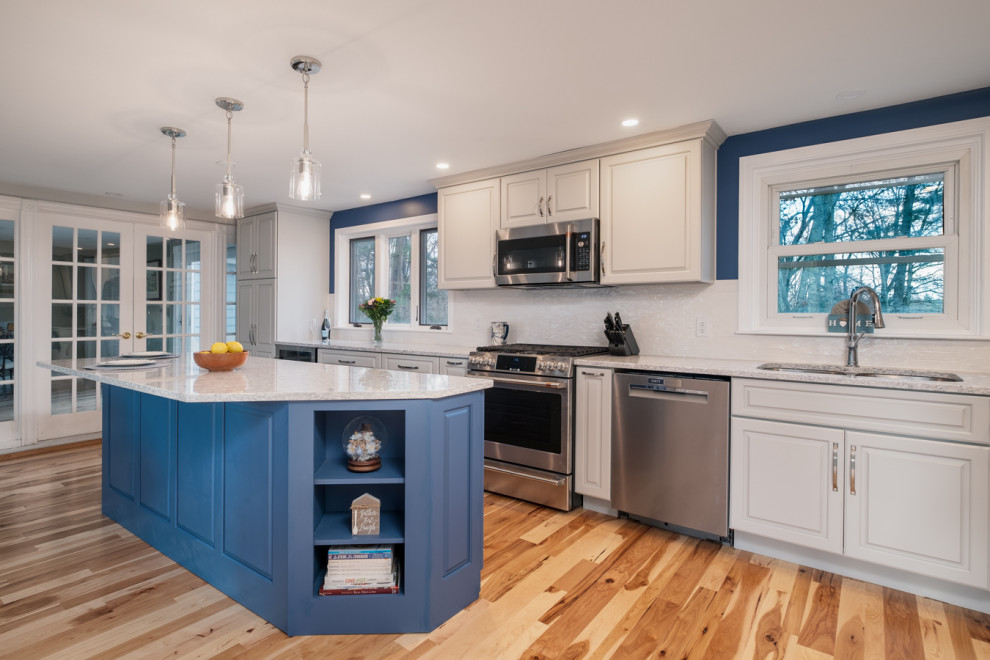 Eat-in kitchen - mid-sized transitional l-shaped light wood floor eat-in kitchen idea in Boston with a single-bowl sink, raised-panel cabinets, gray cabinets, quartz countertops, white backsplash, ceramic backsplash, stainless steel appliances, an island and white countertops
