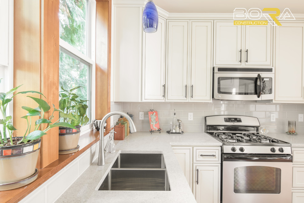 Inspiration for a mid-sized transitional l-shaped medium tone wood floor and brown floor eat-in kitchen remodel with an undermount sink, raised-panel cabinets, white cabinets, quartz countertops, gray backsplash, ceramic backsplash, stainless steel appliances, no island and white countertops