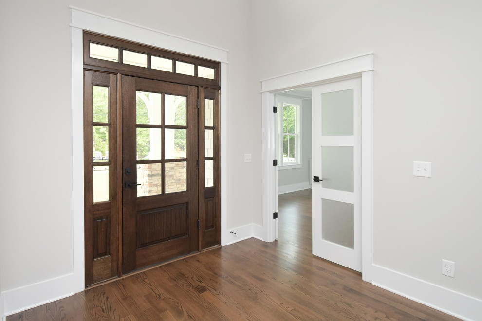 Mid-sized traditional front door in Raleigh with white walls, medium hardwood floors, a single front door, a medium wood front door and brown floor.