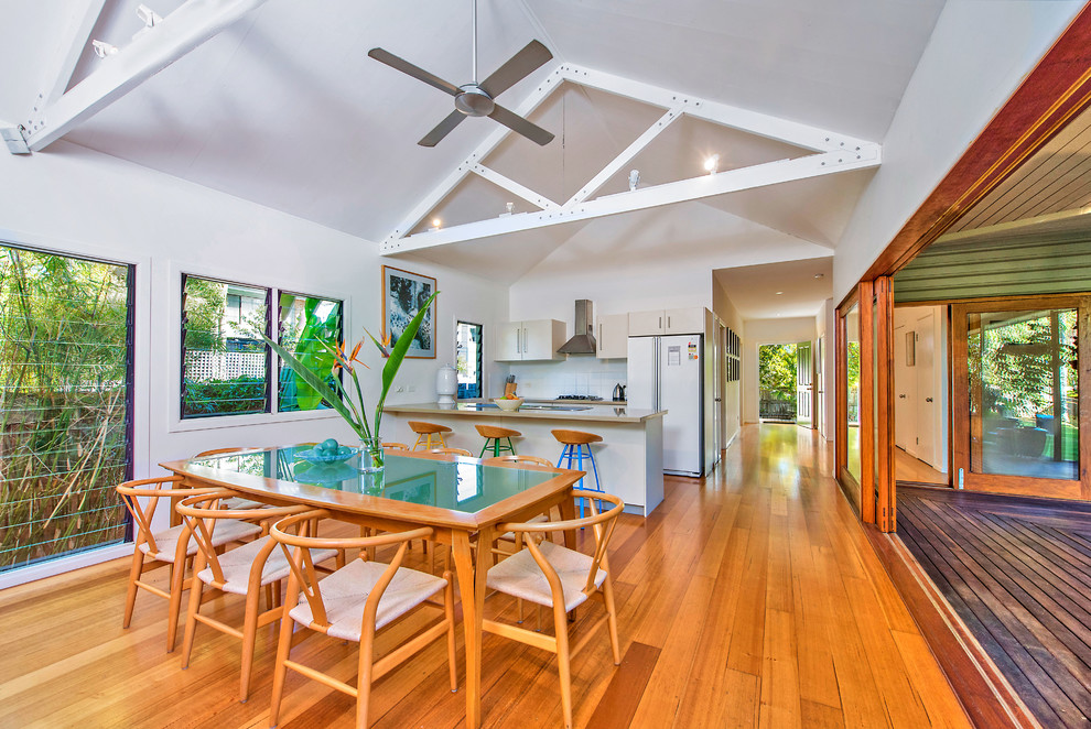 Photo of a tropical open plan dining in Gold Coast - Tweed with white walls and medium hardwood floors.