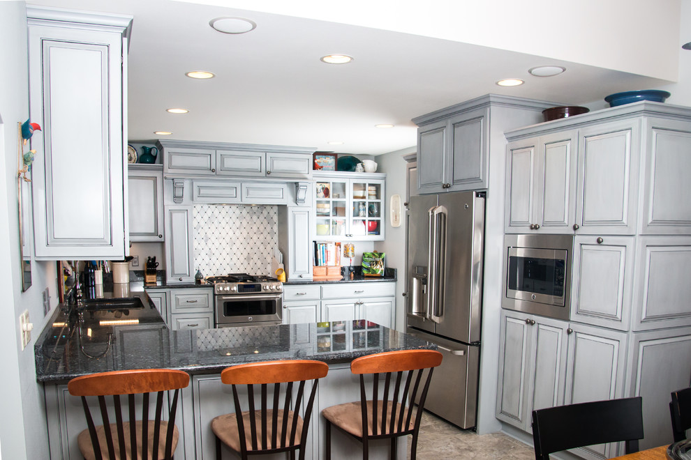 Inspiration for a large transitional u-shaped porcelain tile and beige floor eat-in kitchen remodel in Milwaukee with an undermount sink, raised-panel cabinets, gray cabinets, granite countertops, white backsplash, marble backsplash, stainless steel appliances and no island